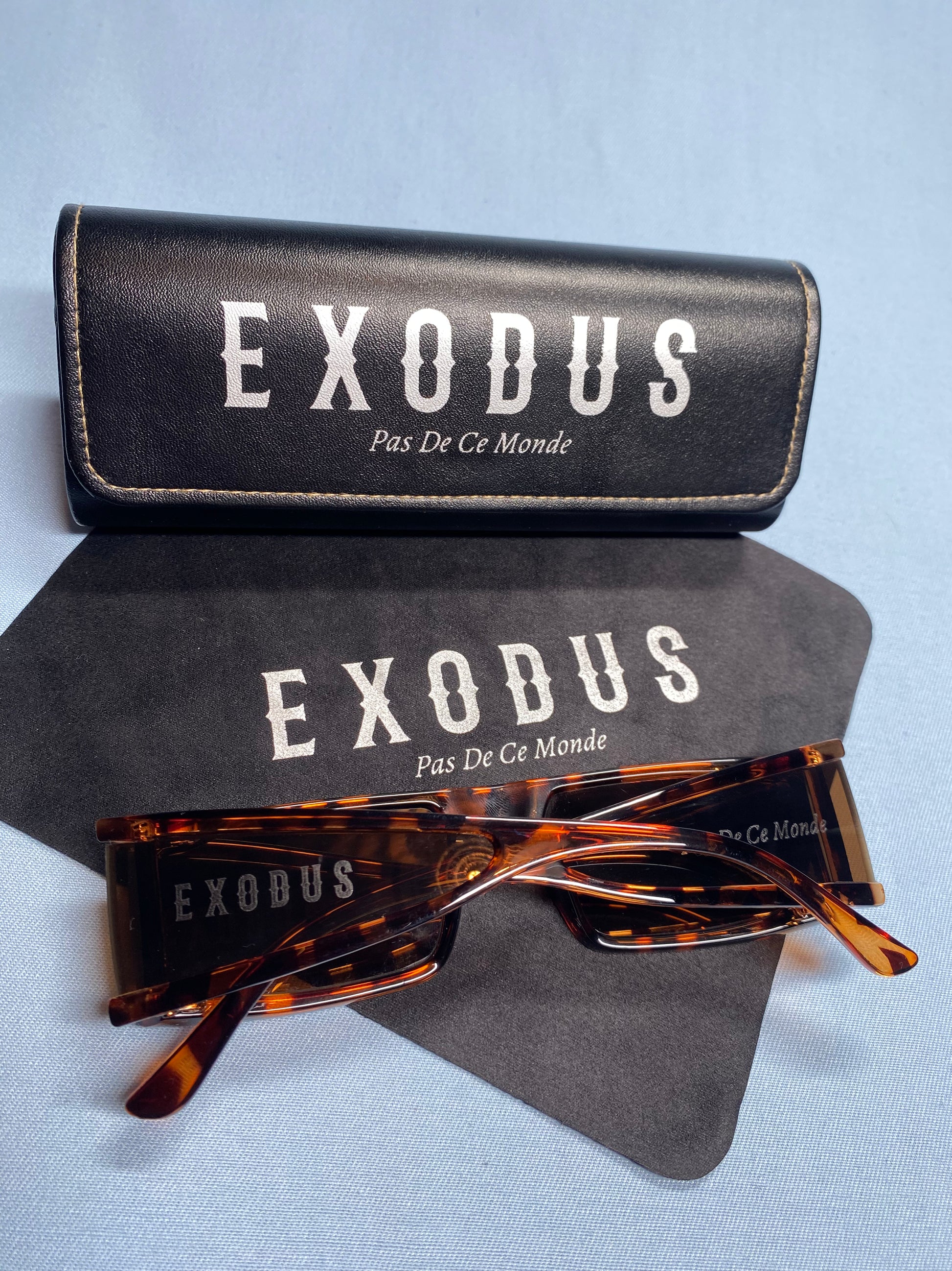 Clothing and accessories from Exodus Pas De Ce Monde – unisex streetwear including t-shirts, jackets, sunglasses, jewelry, bags, and headwear designed for everyday wear and bold urban fashion.